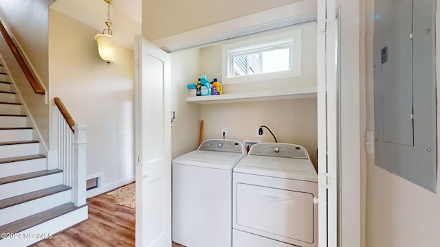 laundry area with washing machine and dryer, electric panel, light wood-style flooring, and laundry area