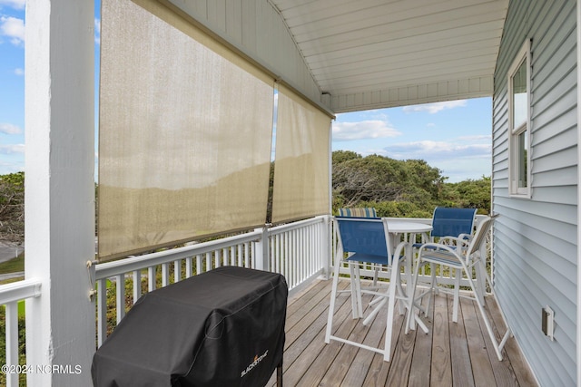 wooden terrace featuring outdoor dining space and a grill