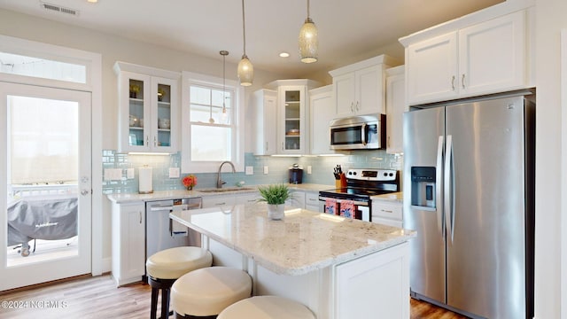 kitchen with plenty of natural light, stainless steel appliances, sink, and a center island