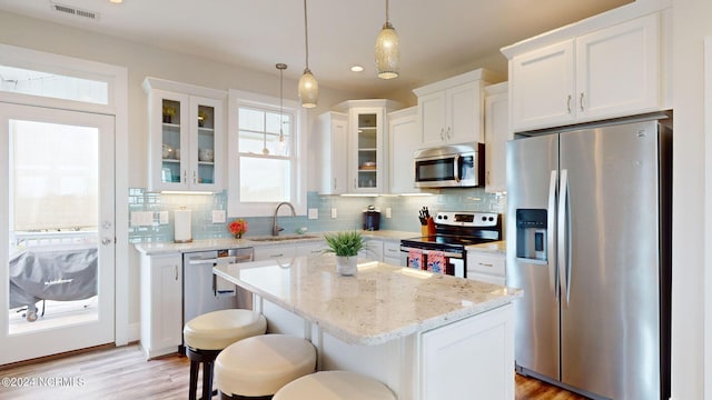 kitchen featuring white cabinets, backsplash, appliances with stainless steel finishes, and a sink