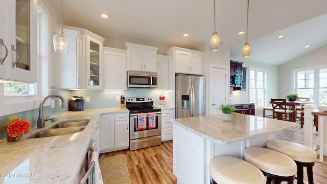 kitchen featuring a wealth of natural light, sink, stainless steel appliances, and white cabinets