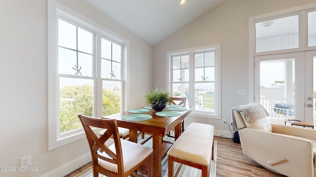 dining area featuring lofted ceiling, light wood finished floors, and baseboards