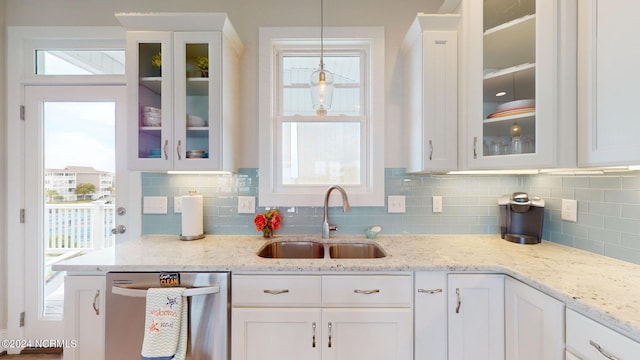 kitchen with dishwasher, pendant lighting, sink, and white cabinetry