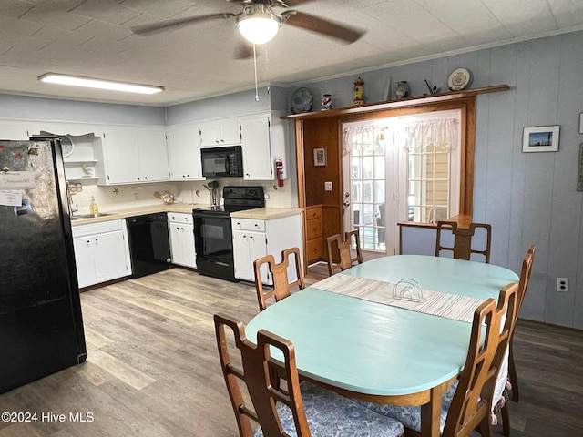 dining room featuring ceiling fan, wood walls, sink, and light hardwood / wood-style flooring