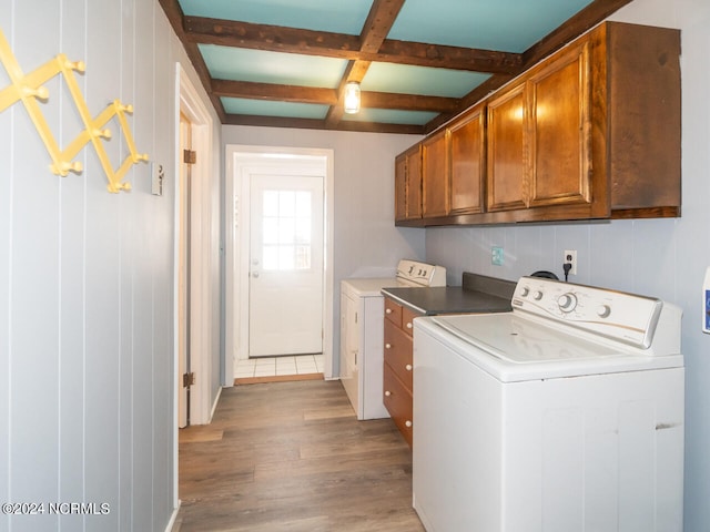 clothes washing area featuring cabinets, separate washer and dryer, and light hardwood / wood-style flooring