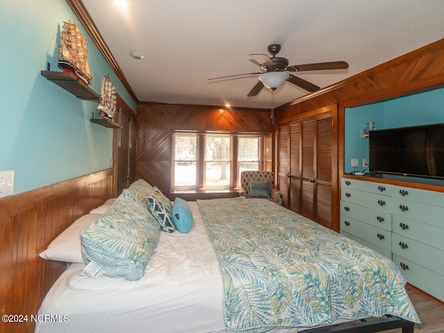 bedroom with wood walls, a closet, and ceiling fan