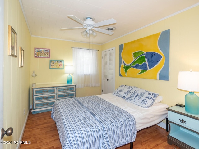 bedroom featuring ceiling fan, wood-type flooring, crown molding, and a closet