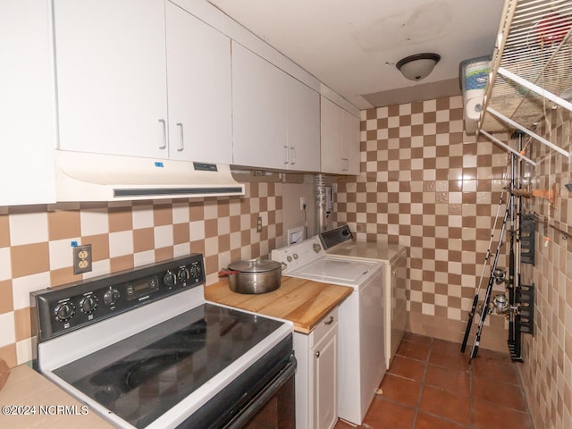 laundry room featuring dark tile patterned floors, washer and clothes dryer, and tile walls