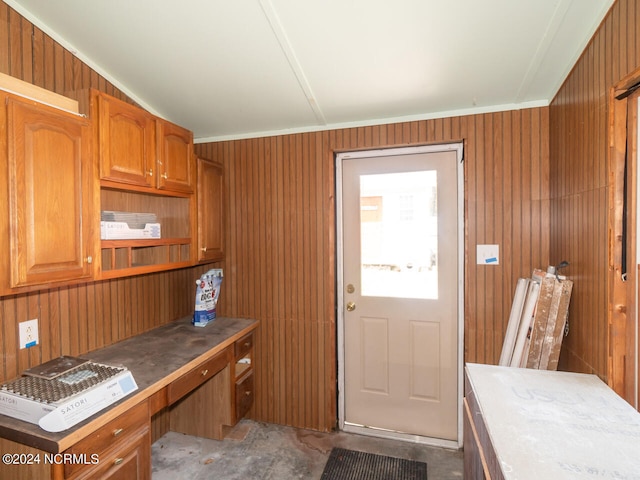 kitchen with wooden walls, concrete flooring, and ornamental molding