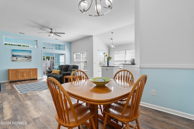 dining room featuring ceiling fan with notable chandelier, dark wood-type flooring, and vaulted ceiling