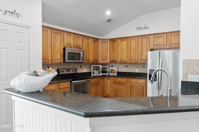 kitchen featuring appliances with stainless steel finishes, kitchen peninsula, vaulted ceiling, and backsplash