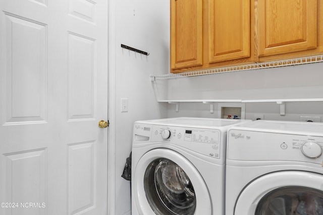 laundry room featuring washing machine and clothes dryer and cabinets