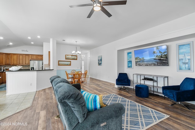 living room with lofted ceiling, ceiling fan with notable chandelier, and hardwood / wood-style flooring