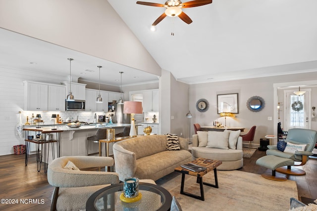 living room featuring high vaulted ceiling, crown molding, sink, ceiling fan, and hardwood / wood-style flooring