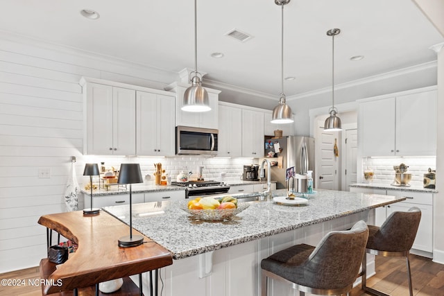 kitchen with hanging light fixtures, ornamental molding, dark hardwood / wood-style floors, appliances with stainless steel finishes, and white cabinets