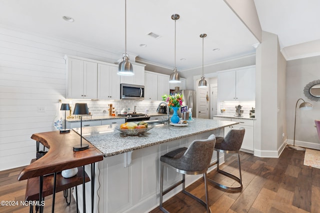 kitchen with white cabinetry, light stone counters, dark wood-type flooring, hanging light fixtures, and appliances with stainless steel finishes