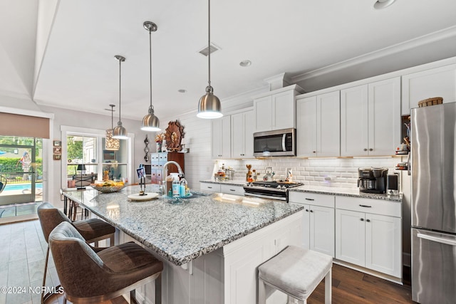 kitchen featuring decorative light fixtures, stainless steel appliances, a center island with sink, and sink