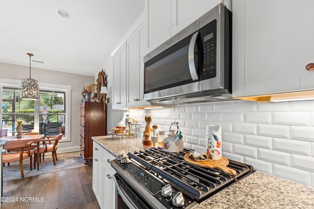 kitchen featuring white cabinetry, stainless steel appliances, light stone counters, an inviting chandelier, and dark hardwood / wood-style floors