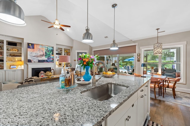 kitchen featuring light stone countertops, dark hardwood / wood-style flooring, sink, white cabinetry, and a healthy amount of sunlight