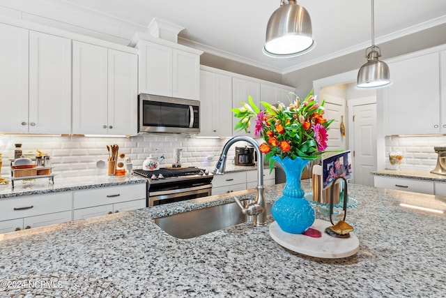 kitchen with white cabinets, appliances with stainless steel finishes, light stone countertops, tasteful backsplash, and ornamental molding