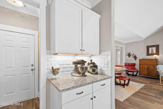 kitchen featuring lofted ceiling, dark hardwood / wood-style floors, light stone countertops, and white cabinetry