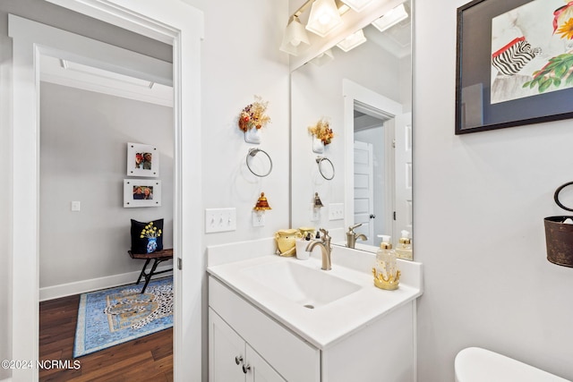 bathroom with hardwood / wood-style floors, toilet, and vanity