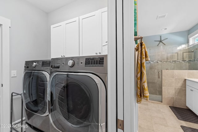 laundry room featuring light tile patterned floors, cabinets, independent washer and dryer, and tile walls