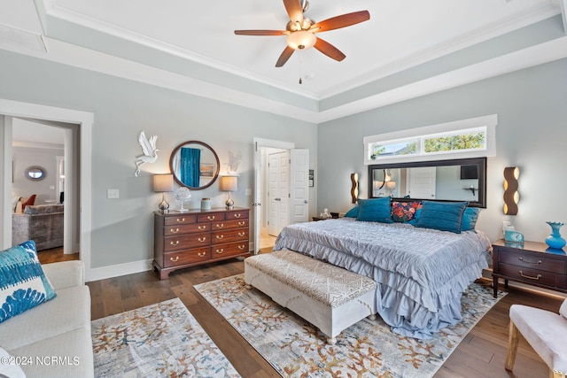 bedroom featuring crown molding, dark wood-type flooring, ceiling fan, and a raised ceiling