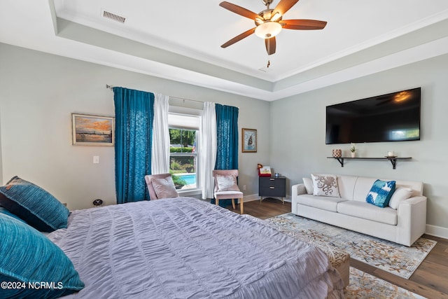 bedroom with crown molding, a raised ceiling, ceiling fan, and wood-type flooring