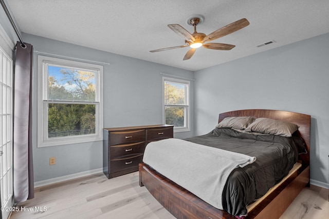 bedroom featuring ceiling fan, light hardwood / wood-style flooring, and a textured ceiling