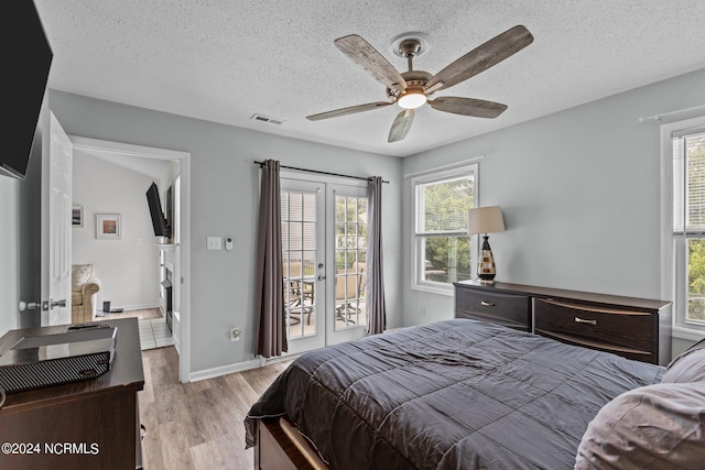 bedroom featuring access to exterior, french doors, a textured ceiling, ceiling fan, and light hardwood / wood-style floors