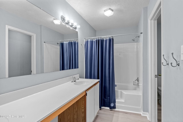 full bathroom featuring shower / bath combination with curtain, vanity, a textured ceiling, hardwood / wood-style flooring, and toilet