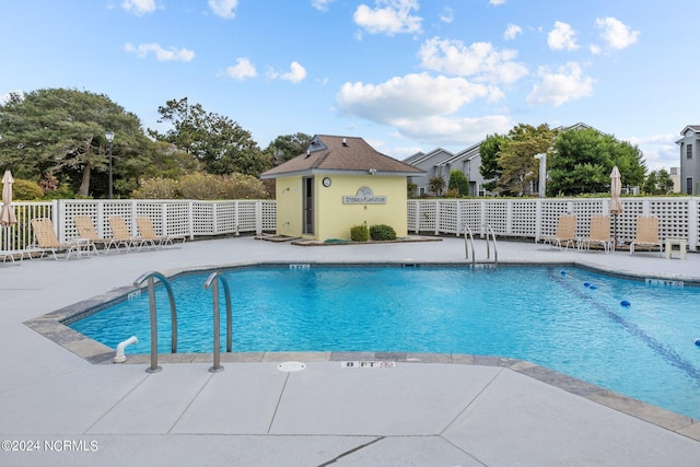 view of swimming pool featuring a patio area and an outbuilding