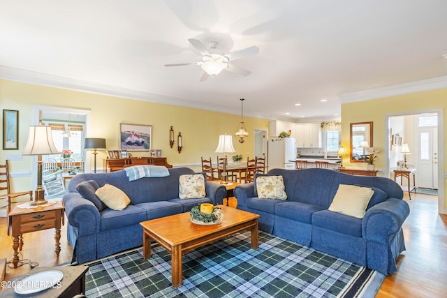 living room featuring crown molding, ceiling fan, and light hardwood / wood-style floors