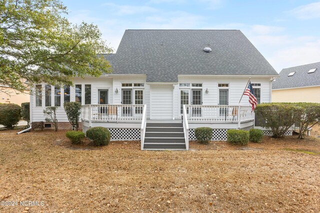 rear view of property featuring a wooden deck and a lawn