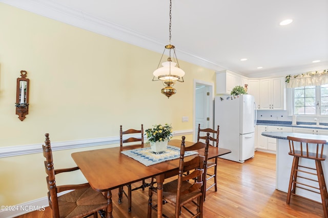 dining area with light hardwood / wood-style flooring, ornamental molding, and sink