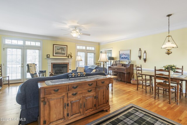 living room featuring light hardwood / wood-style flooring, ceiling fan, ornamental molding, and a healthy amount of sunlight