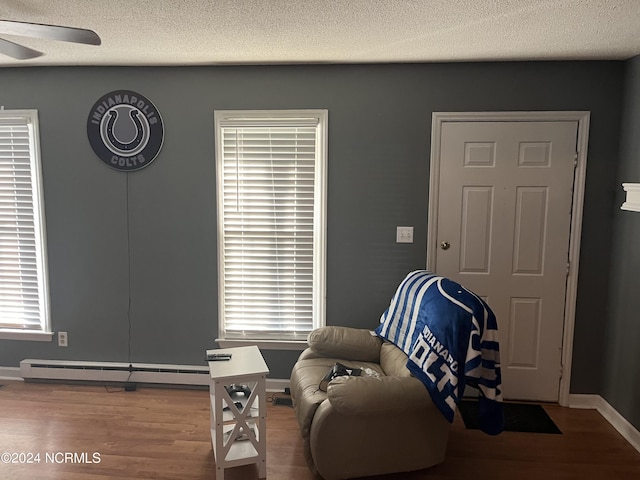 sitting room with baseboard heating, wood-type flooring, and ceiling fan