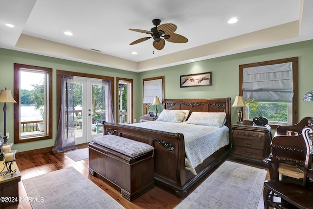 bedroom with a raised ceiling, access to outside, multiple windows, and french doors