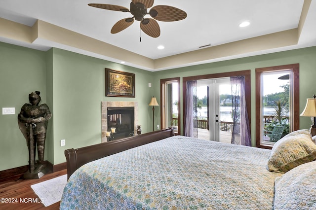 bedroom featuring wood finished floors, visible vents, baseboards, a fireplace, and access to exterior