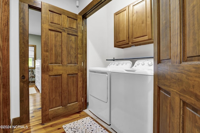 laundry room with light wood finished floors, cabinet space, and separate washer and dryer