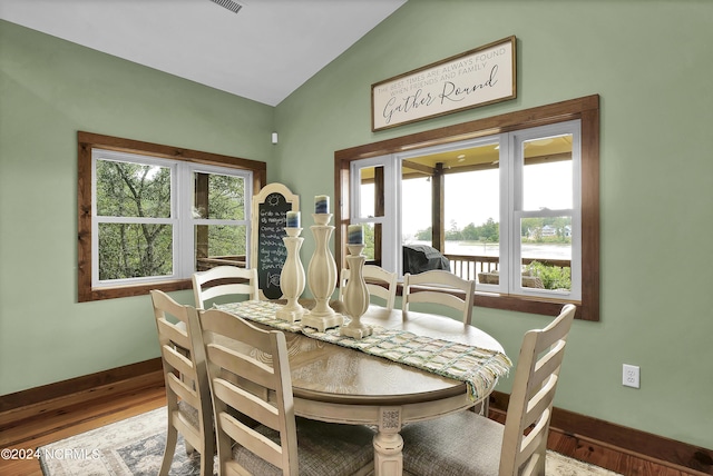 dining space with baseboards, wood finished floors, and vaulted ceiling