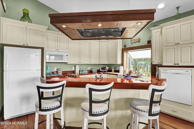 kitchen with dark countertops, white appliances, white cabinetry, and wood finished floors