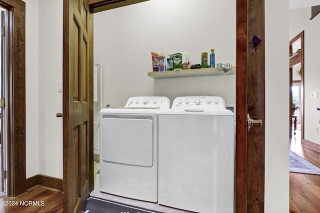 laundry area with washing machine and clothes dryer, laundry area, baseboards, and wood finished floors