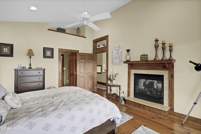 bedroom with wood finished floors, a tile fireplace, and vaulted ceiling