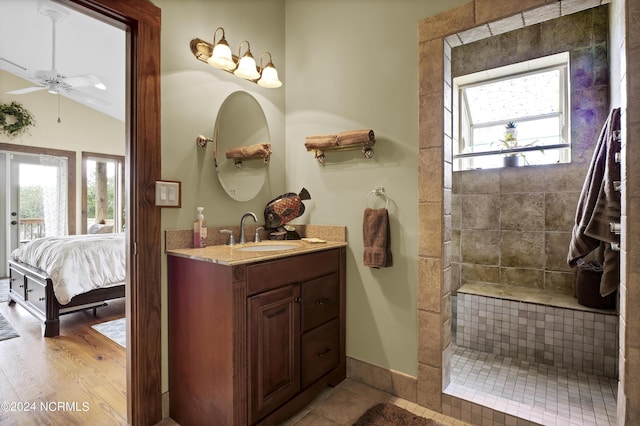 full bathroom with vanity, wood finished floors, tiled shower, lofted ceiling, and ensuite bathroom