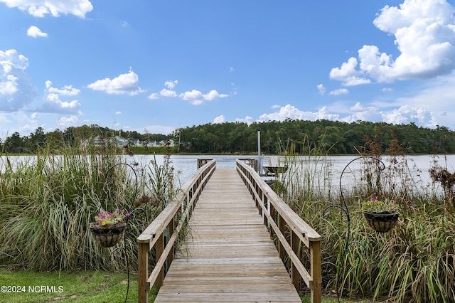 view of dock with a wooded view and a water view