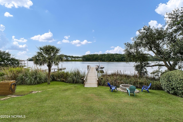 view of yard featuring an outdoor fire pit, a boat dock, and a water view