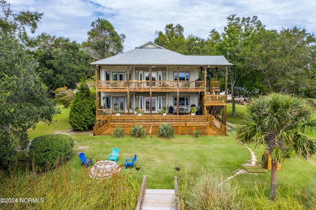 rear view of house with a wooden deck, an outdoor fire pit, stairs, french doors, and a yard