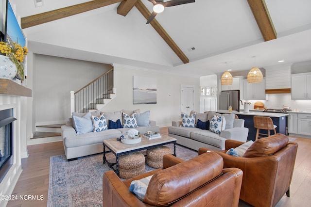 living room featuring high vaulted ceiling, beamed ceiling, and light wood-type flooring